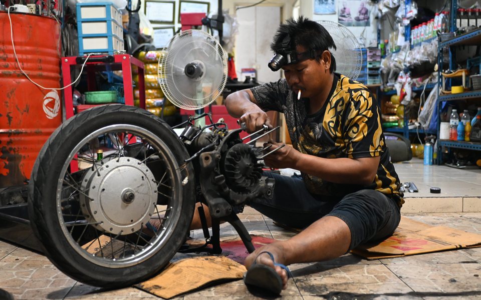 Montir membongkar mesin motor di bengkel
